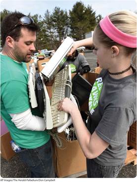 A photo shows a man and a woman taking out preowned keyboards and other electronic equipment from cartons.